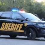 Police vehicle near a rural road during a law enforcement search in Branch County