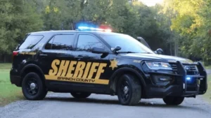 Police vehicle near a rural road during a law enforcement search in Branch County